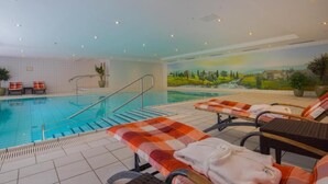 A swimming pool area with lounge chairs and a mural on the wall. - New Living Home Residenzhotel Hamburg (Hamburg)