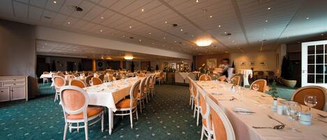 Un amplio salón de banquetes con varias mesas largas dispuestas para comer, organizadas en filas.