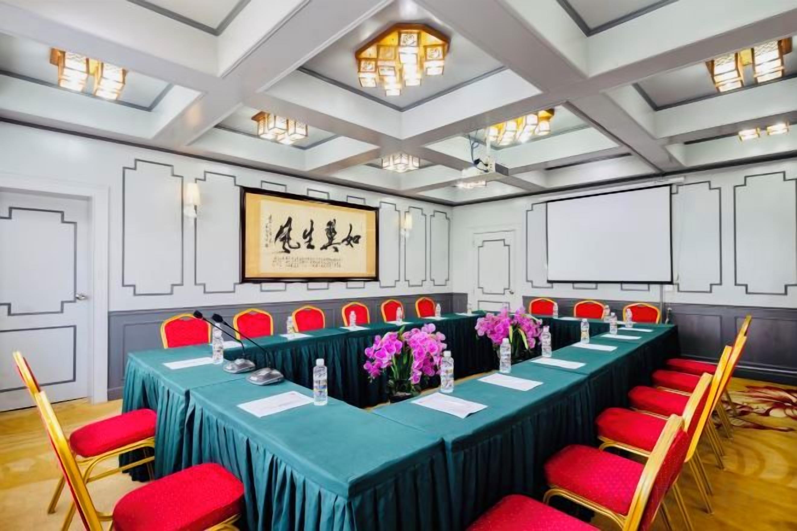A conference room with a long table, red chairs, and a framed artwork on the wall.
