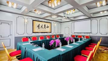 A conference room with a long table, red chairs, and a framed artwork on the wall.