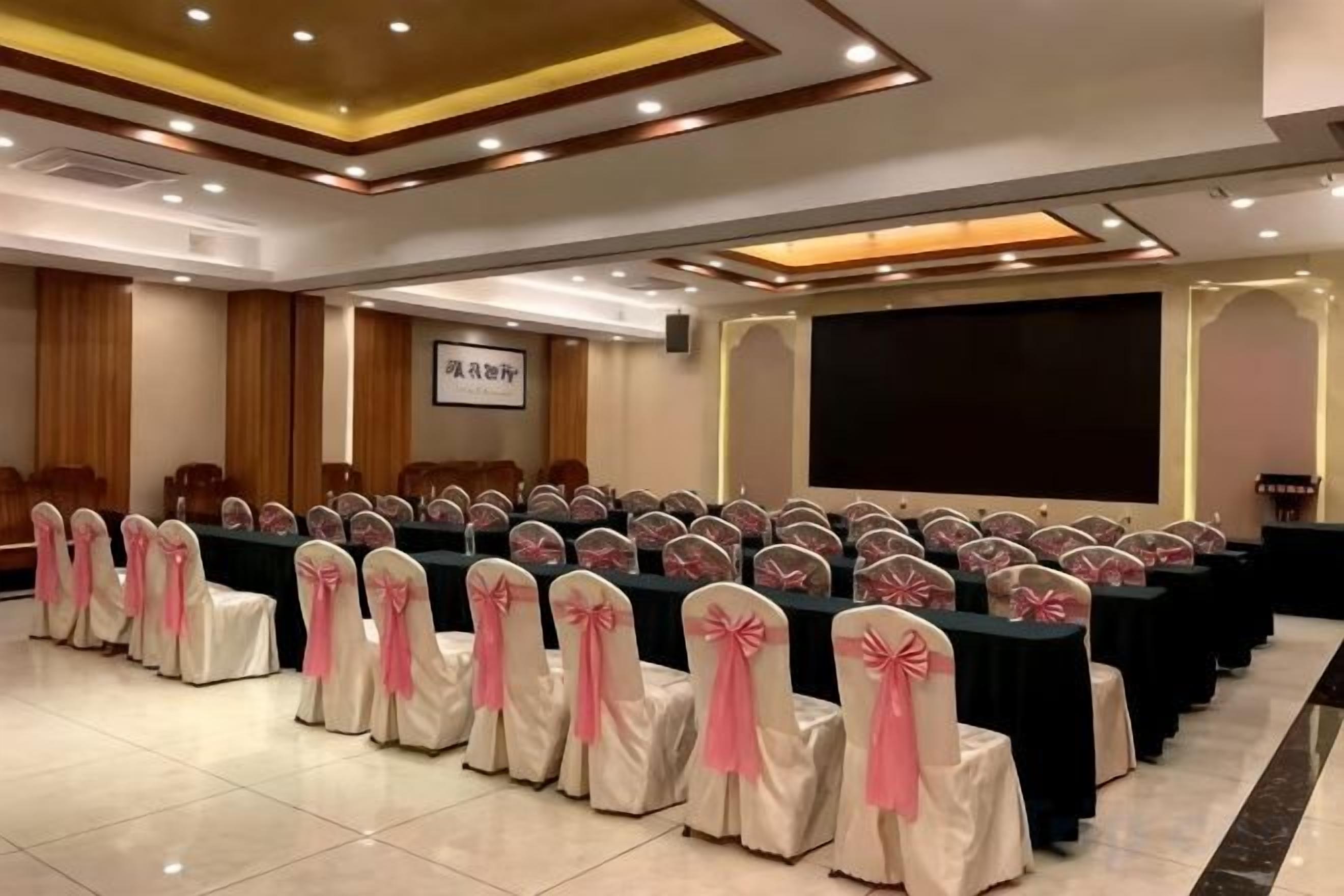 A conference room with rows of tables and chairs, a projection screen, and a podium.