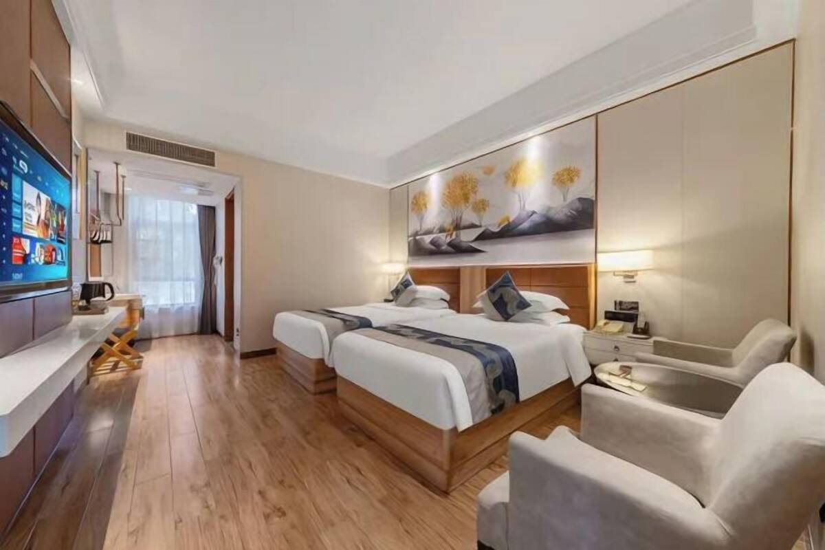 A hotel room with two beds, a TV, a desk, and a chair.