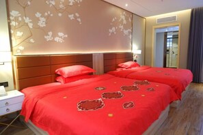 A hotel room with two beds, a wooden floor, and a wall with floral wallpaper. - Longquan Garden Hotel (Haikou Pearl Square Qilou Old Street Branch) (Haikou)