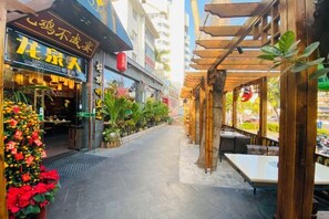 Un étroit couloir extérieur, avec un restaurant situé sur la gauche, où l’on peut voir une enseigne indiquant « Poulet au lait de coco de Longquan ».