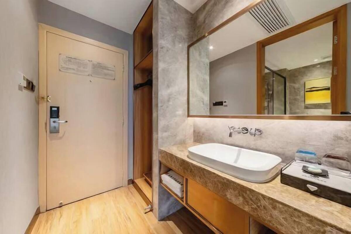 A modern bathroom with a marble countertop, a sink, and a large mirror.