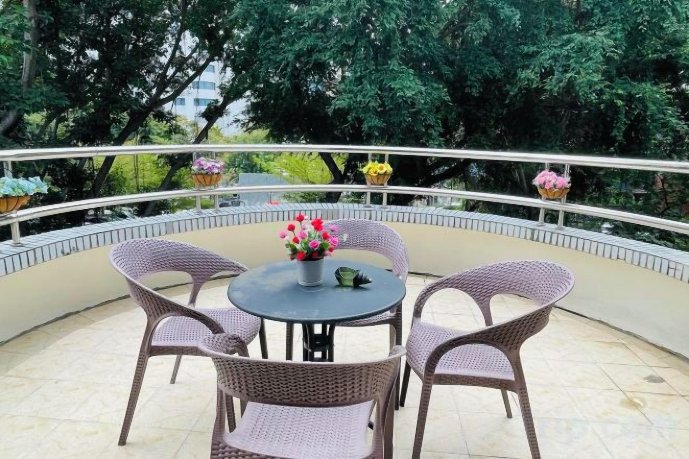 Une table ronde d’extérieur, entourée de chaises en osier et de plantes en pot.