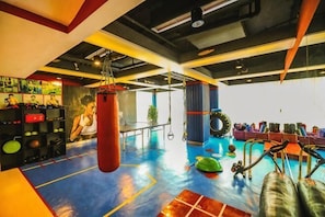 Een sportschool met trainingsapparatuur, een bokszak en een blauwe vloer.