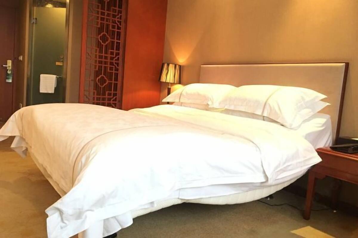 Una cama bien hecha con sábanas blancas en una habitación de hotel.