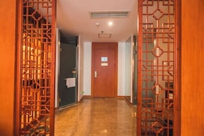A hallway with a wooden door, a vent on the ceiling, and a tiled floor. - Cangxi International Hotel (Cangxi)