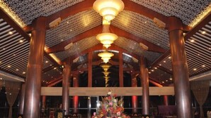 A spacious lobby with high ceilings, ornate ceiling patterns, and a central floral arrangement. - Cangxi International Hotel (Cangxi)