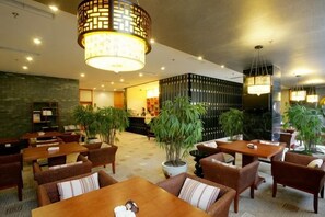 A hotel lobby with seating arrangements, a reception desk, and decorative plants. - Cangxi International Hotel (Cangxi)