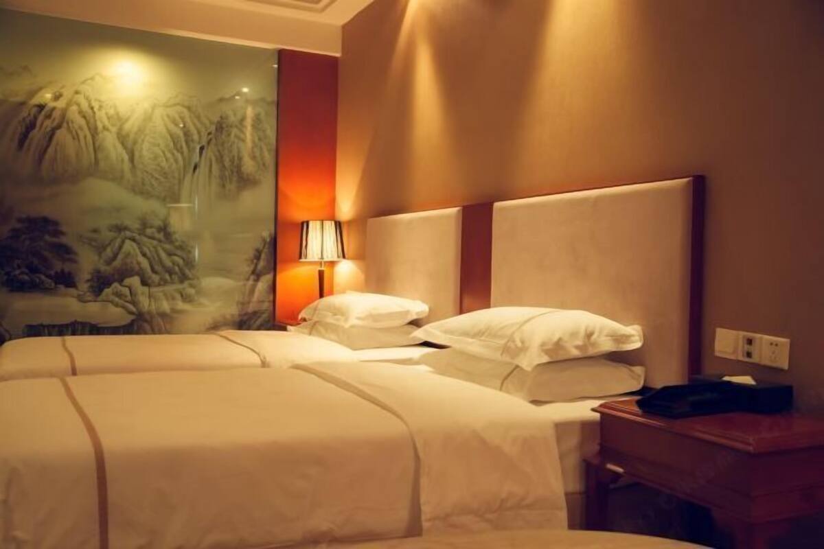 Una habitación de hotel con una cama grande, una mesita de noche, una lámpara y un mural en la pared.