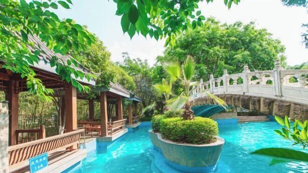 A serene indoor pool area with a stone bridge, lush greenery, and a wooden pavilion. - Cangxi International Hotel (Cangxi)