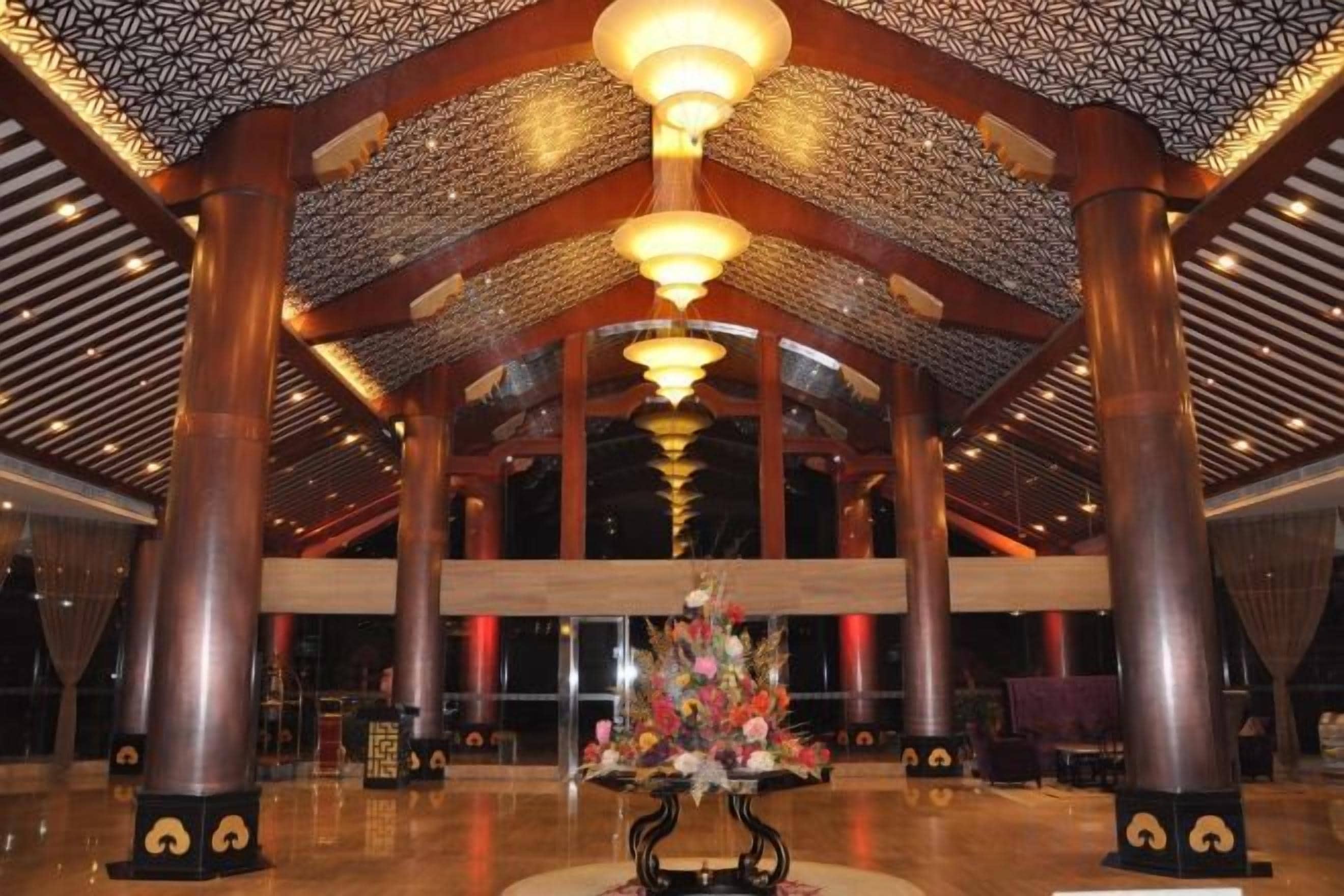 A spacious lobby with high ceilings, large columns, and a central floral arrangement.