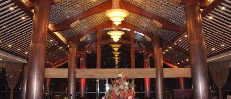 A spacious lobby with high ceilings, large columns, and a central floral arrangement.