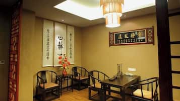 A traditional dining room with a wooden table and chairs, a hanging light fixture, and calligraphy on the walls.