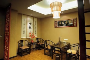 A traditional dining room with a wooden table and chairs, a hanging light fixture, and calligraphy on the walls. - Cangxi International Hotel (Cangxi)
