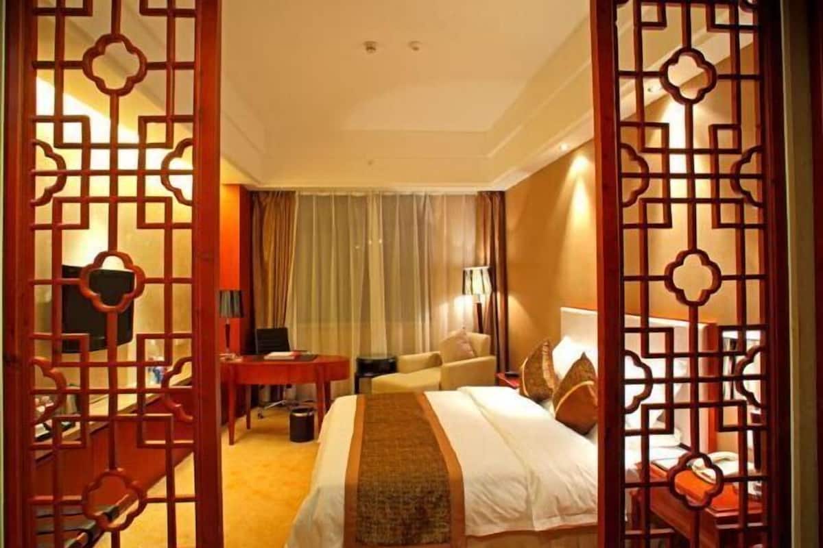 Una habitación de hotel con una cama, un escritorio, una silla y un televisor.