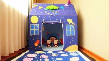 Una casita de juegos con un tobogán, dos osos de peluche en su interior y un tema de noche estrellada.