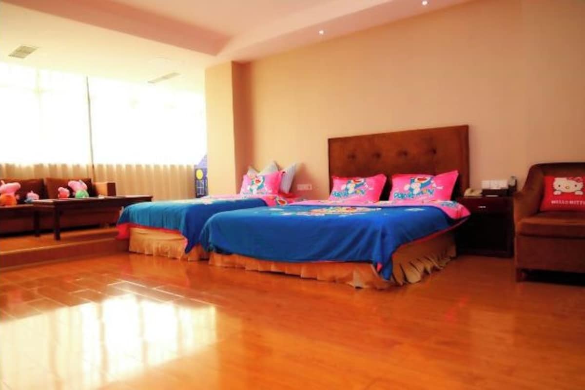 A hotel room with two beds, a sofa, and a window with curtains.
