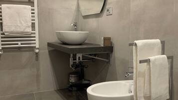 Un baño moderno con un lavamanos tipo recipiente, inodoro y bidé.