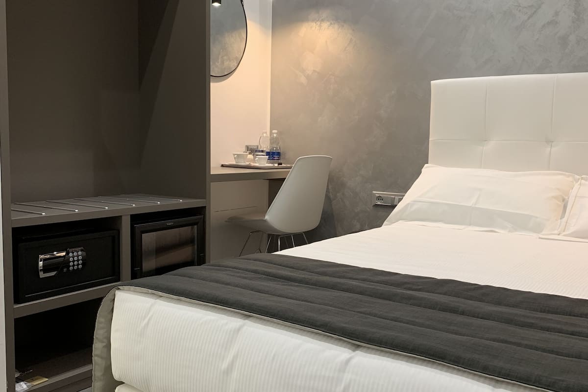 Un dormitorio moderno con una cama grande, un escritorio con silla, un armario y un espejo.