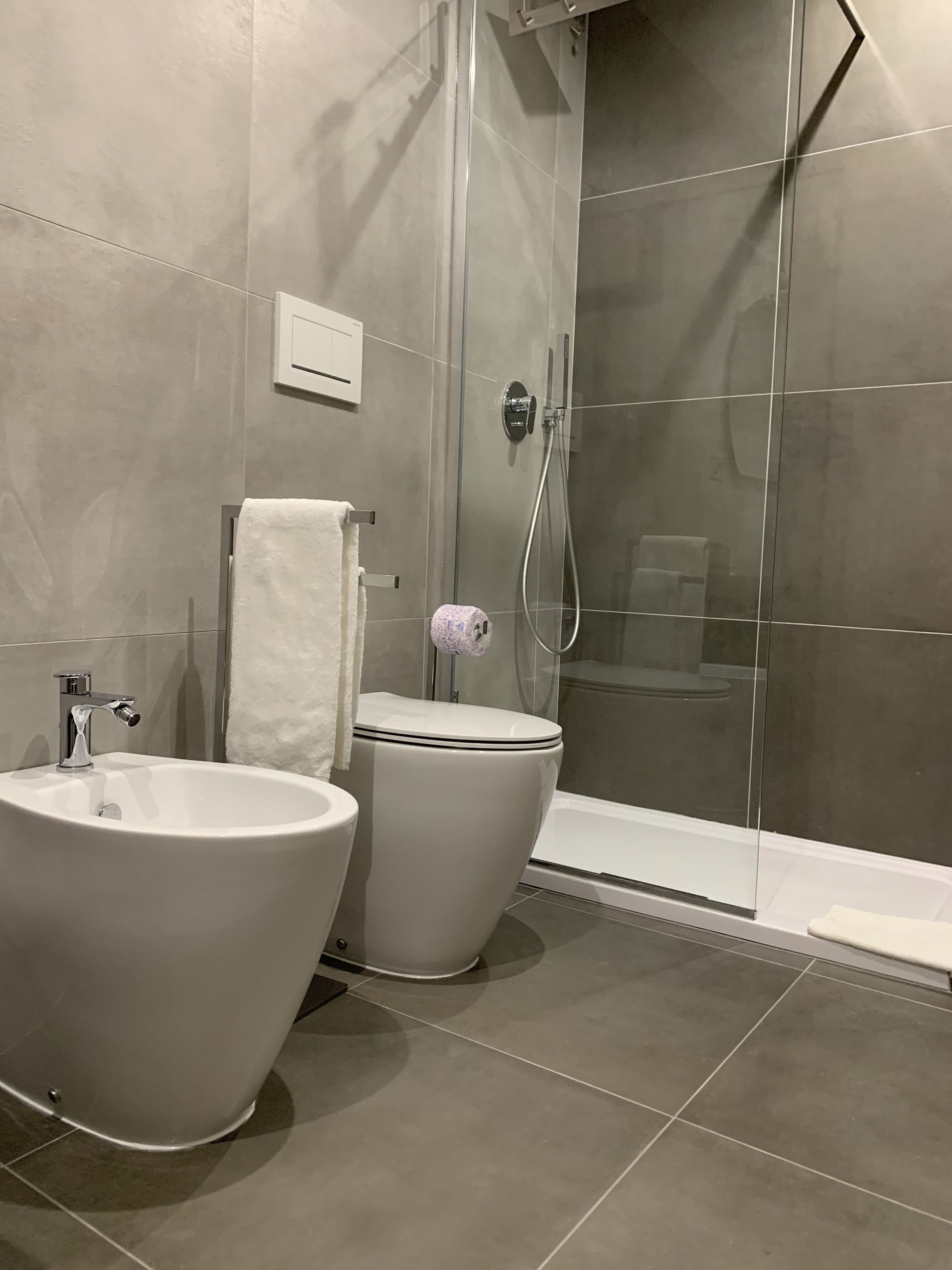 A modern bathroom with a freestanding bathtub, a toilet, and a glass-enclosed shower area.