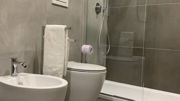 Een moderne badkamer met een vrijstaand bad, een toilet en een douchecabine met glazen wanden.