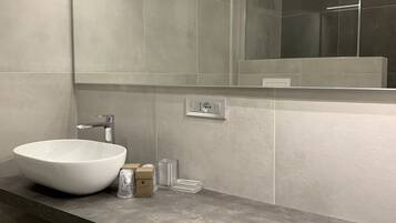 A modern bathroom with a large mirror, a white vessel sink, and a sleek countertop.