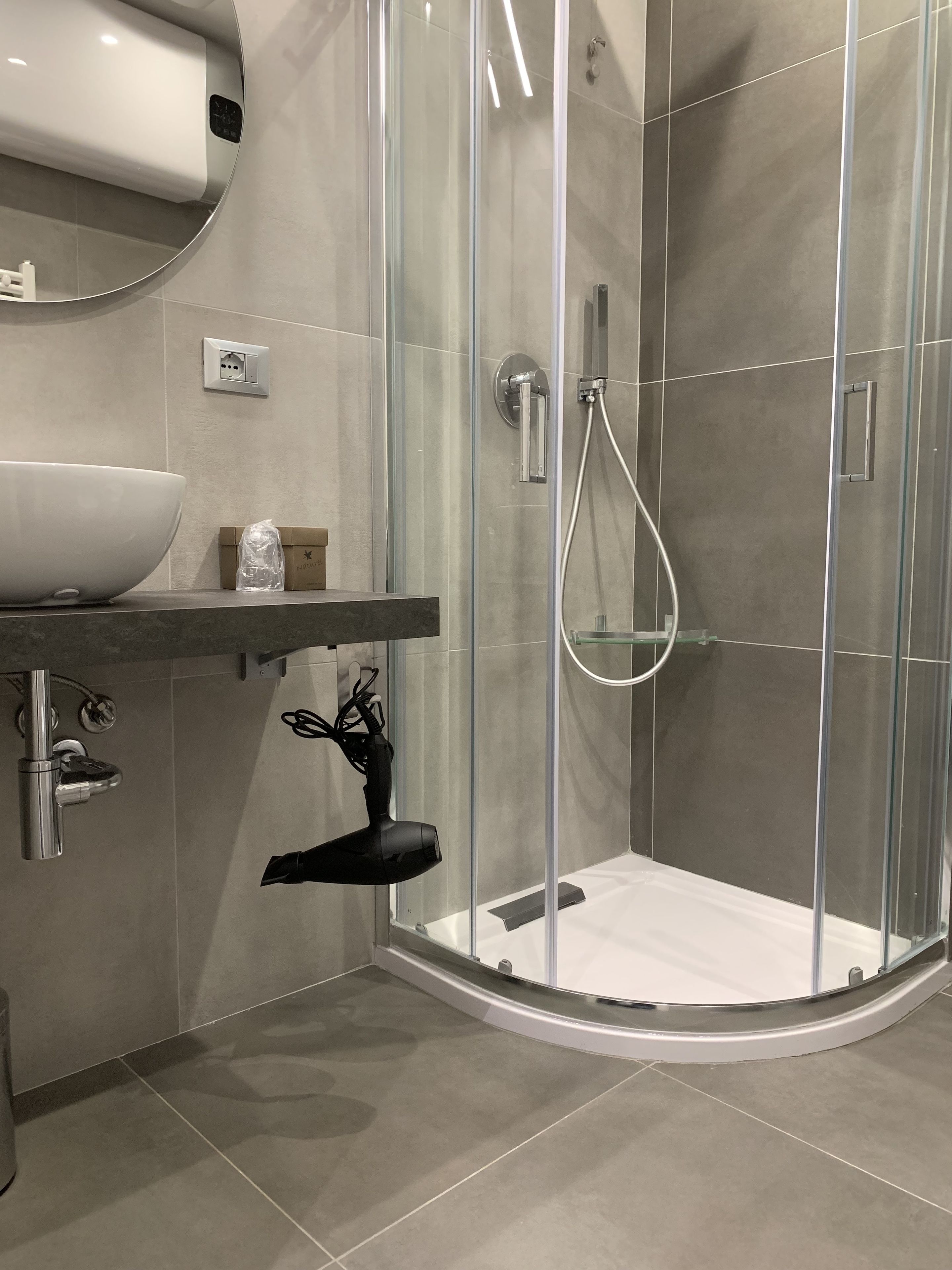 A modern bathroom with a glass-enclosed shower, a large white basin, and a towel rack.