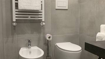 Un baño moderno con bidé, inodoro, toallero y panel de control.