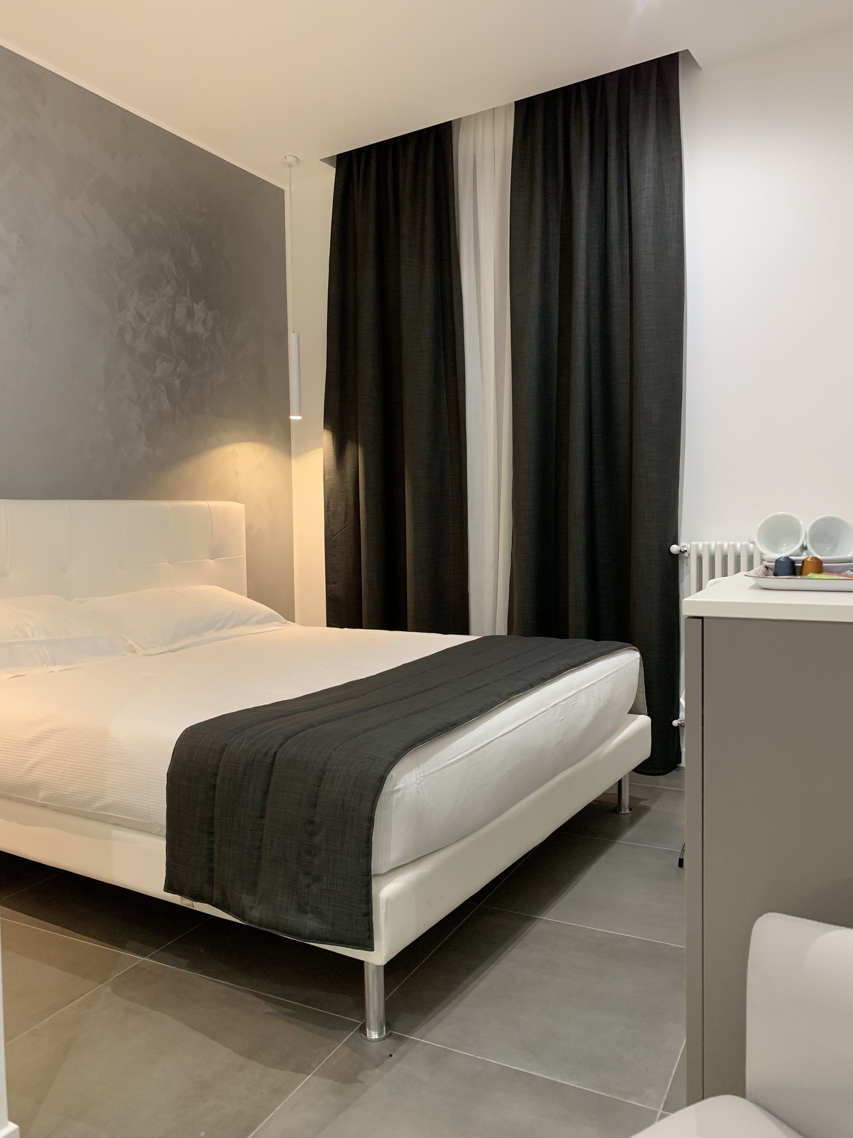 A modern hotel room with a bed, a desk, and a mirror.