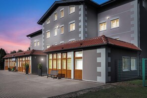A modern building with a grey facade, multiple windows, and a red-tiled roof. - Hotel Muenkel (Hannover)