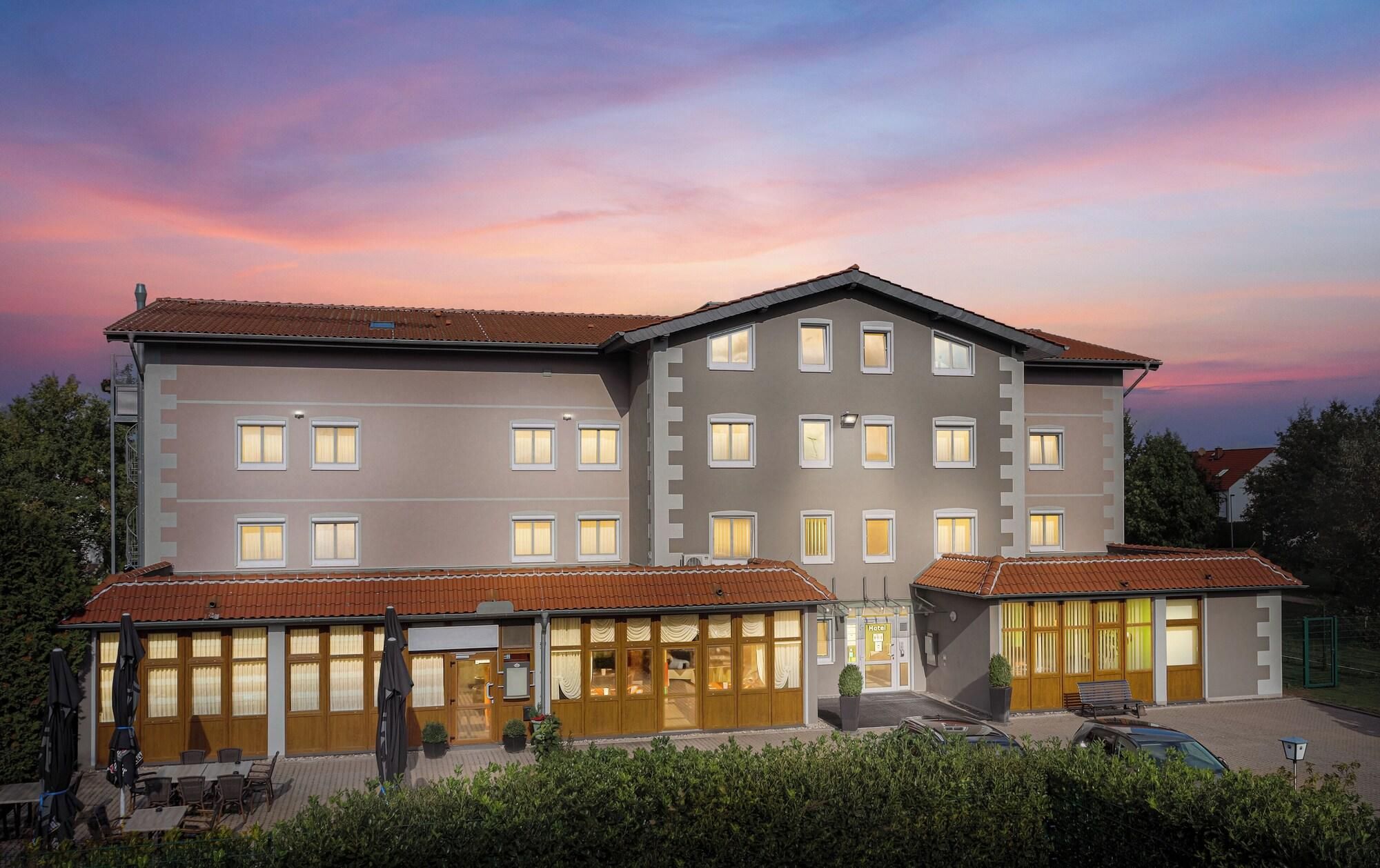 Um hotel com estrutura em dois andares, várias janelas e telhado de telhas vermelhas.