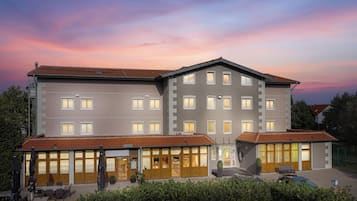 Um hotel com estrutura em dois andares, várias janelas e telhado de telhas vermelhas.