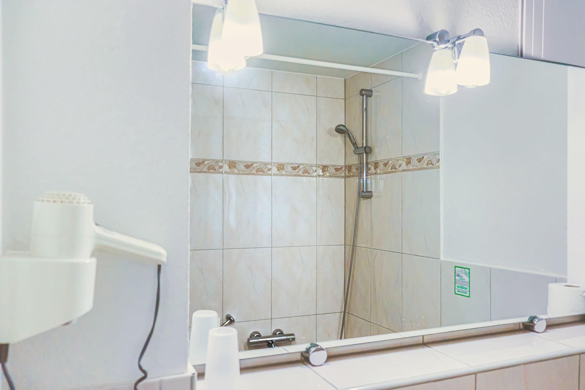 Ein Badezimmer mit Dusche, Spiegel und Handtuchhalter.
