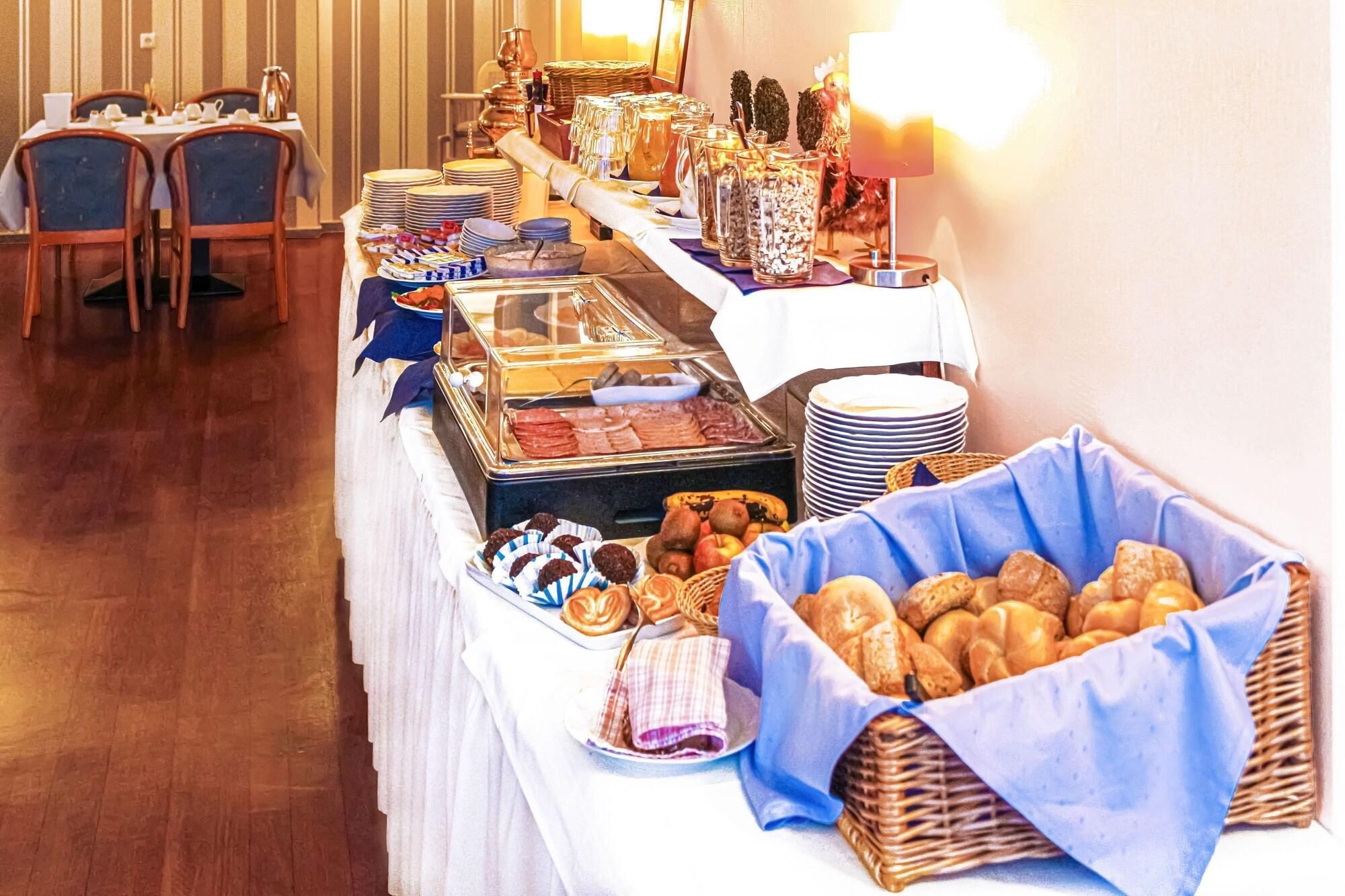 Een buffetopstelling met diverse gerechten, waaronder gebak en fruit, en een koffiehoek.