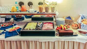 Uma mesa de buffet com diversos alimentos, incluindo carnes, saladas e doces.