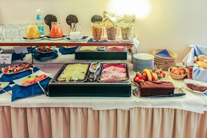 A buffet table with various food items, including meats, salads, and pastries. - Hotel Muenkel (Hannover)