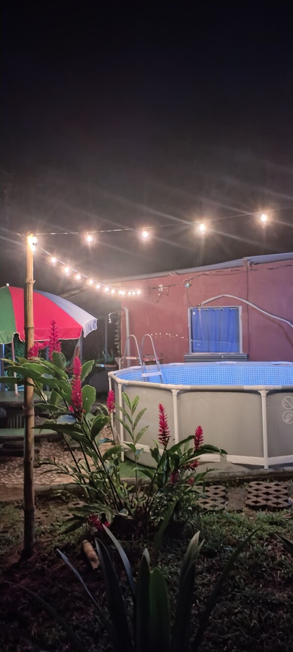 A swimming pool with a blue cover, surrounded by plants and a red umbrella. - Cabinasyafethosa caletas (Drake Bay)