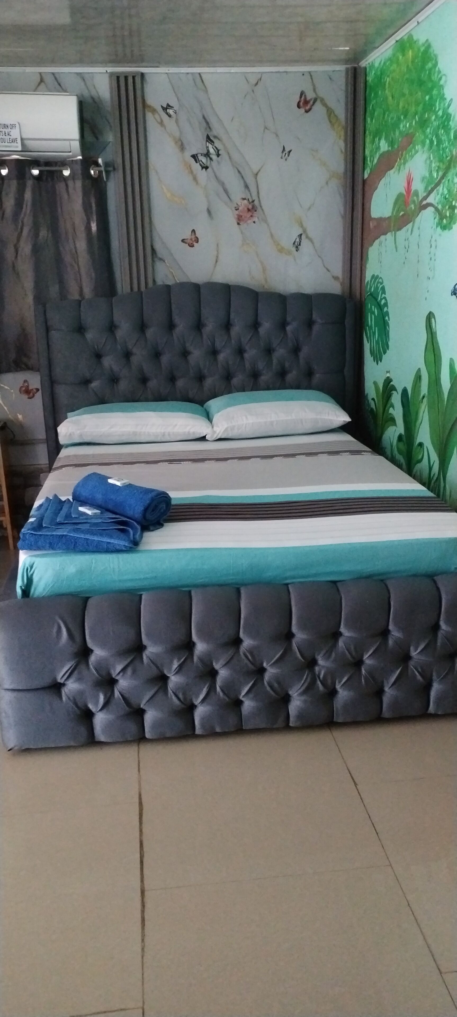 A bed with a tufted headboard, a teal and white mattress, and blue towels.