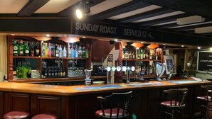 A bar area with a sign indicating 'Sunday Roast Served 12-4pm'. There are multiple liquor bottles and a beer tap labeled 'Guinness'. - Halfway House (Blackwood)