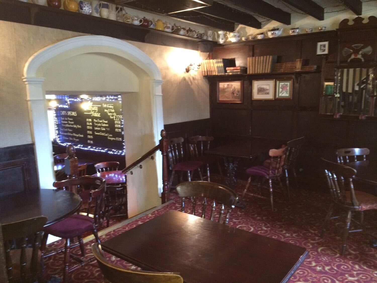 Interior de restaurant amb taules i cadires de fusta, un paviment estampat i un menú escrit a la pissarra.