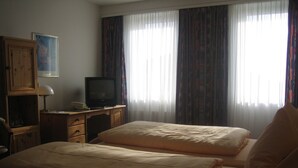 A hotel room with two beds, a desk with a television, and a window with curtains. - Neustädter Hof Hotel Garni (Neustadt am Ruebenberge)