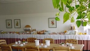 A dining area with wooden tables and chairs, a buffet table in the background, and framed pictures on the wall. - Neustädter Hof Hotel Garni (Neustadt am Ruebenberge)