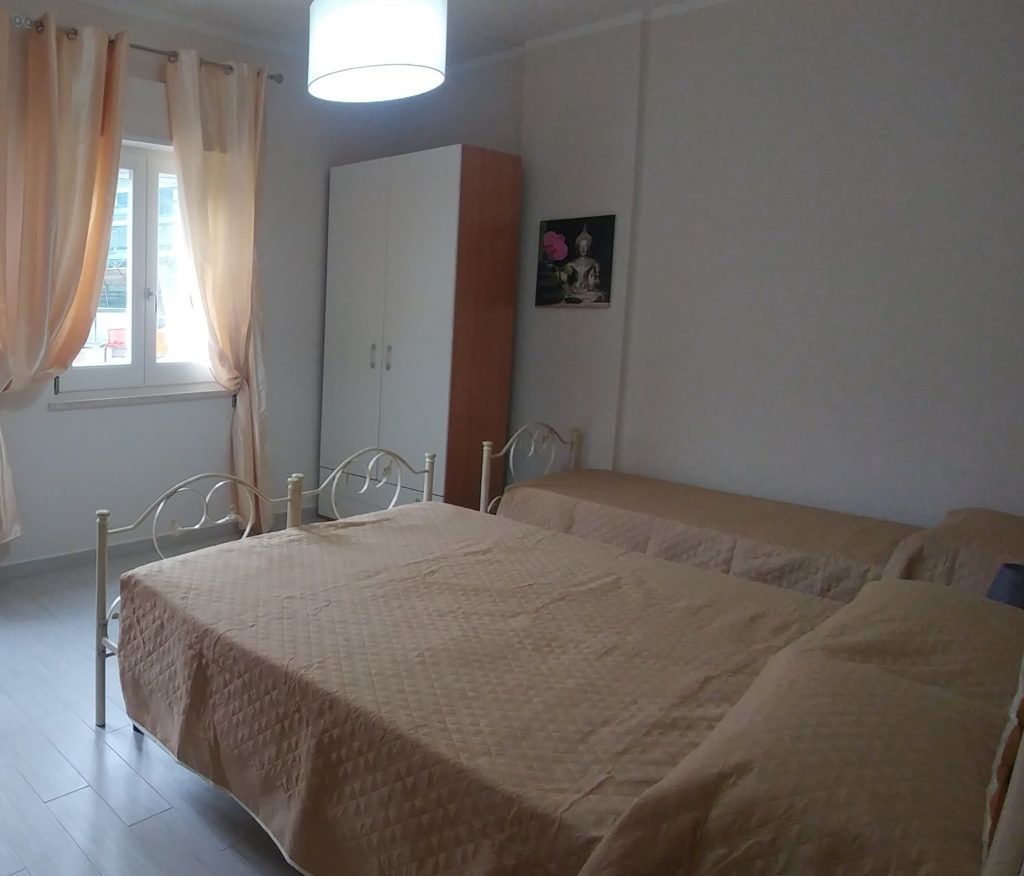 Un dormitorio con cama, armario, ventana con cortinas e imagen colgada en la pared.