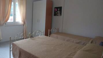 Un dormitorio con cama, armario, ventana con cortinas e imagen colgada en la pared.