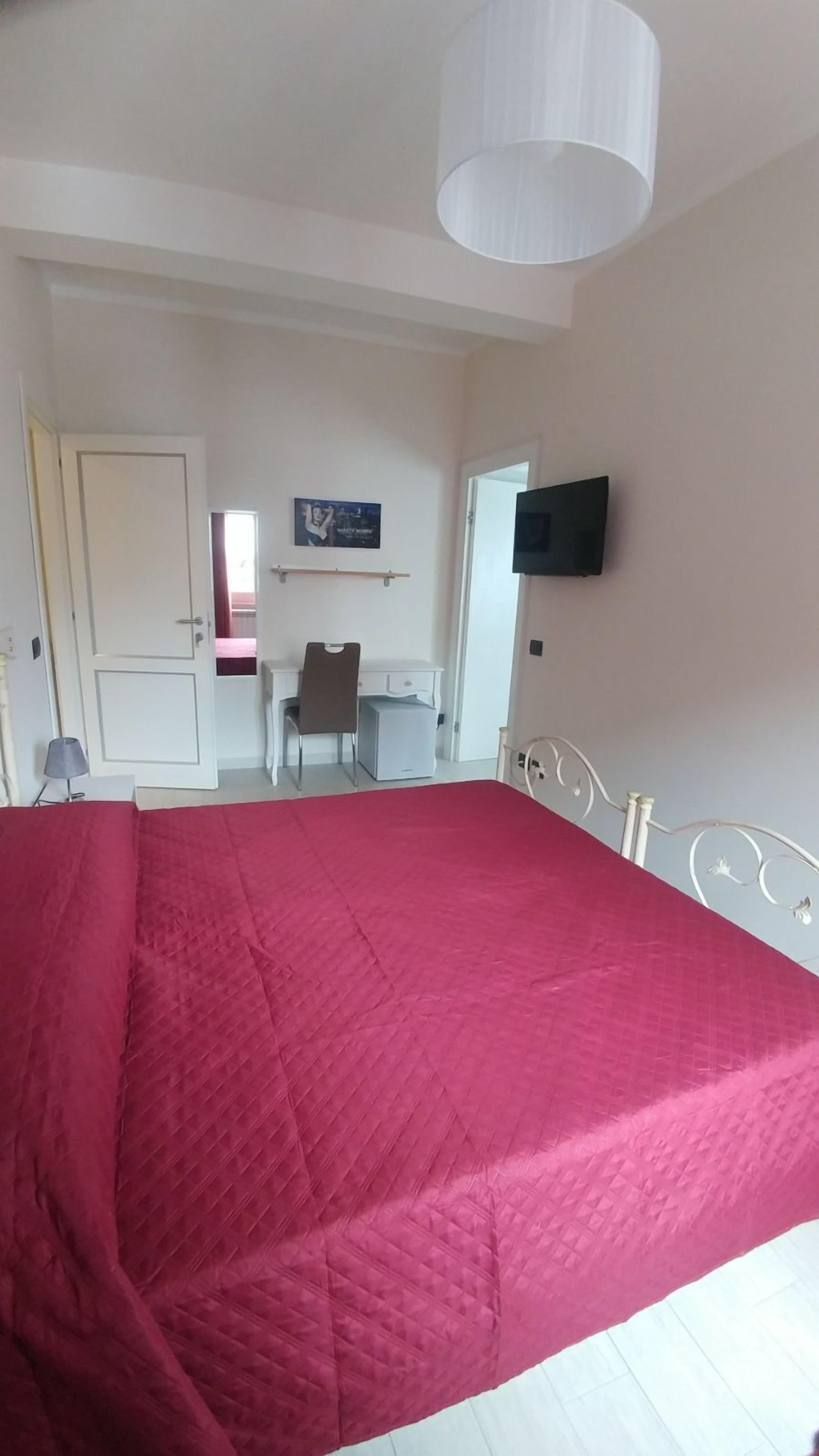 A bedroom with a bed, a television, and a door leading to another room.