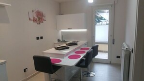 A modern kitchen with a central island, pendant lighting, and a view to the outside. - B&B I Portici (Catanzaro)