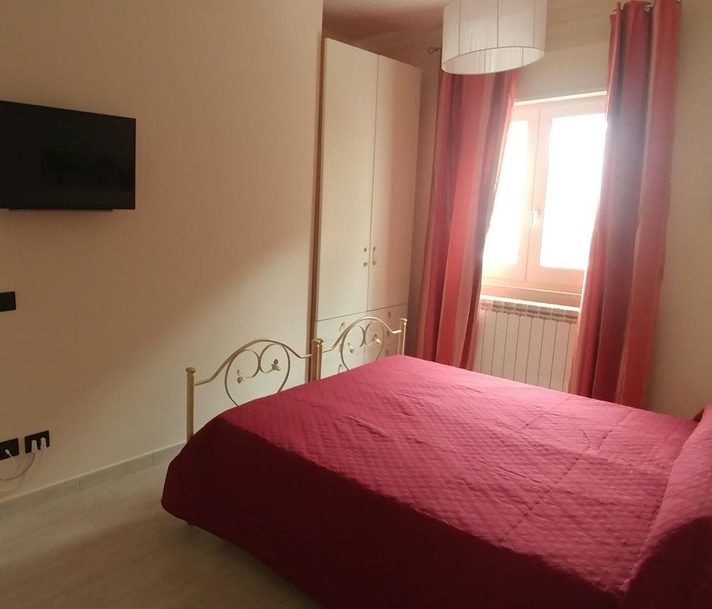 Un dormitorio con cama, armario y ventana con cortinas.